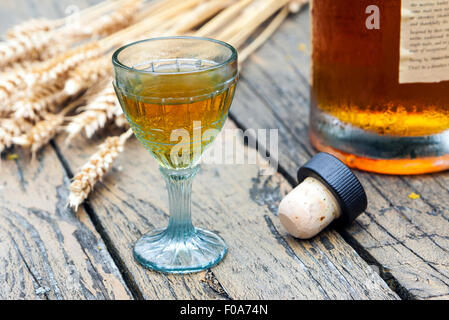 Vintage crystal brandy glass with bottle, cork and rye in the background Stock Photo
