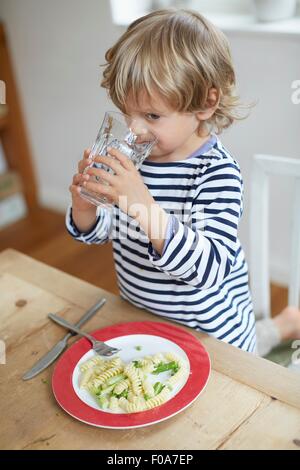 Boy drinking water at dining table Stock Photo