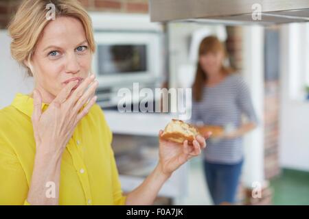 Women eating cake in kitchen Stock Photo