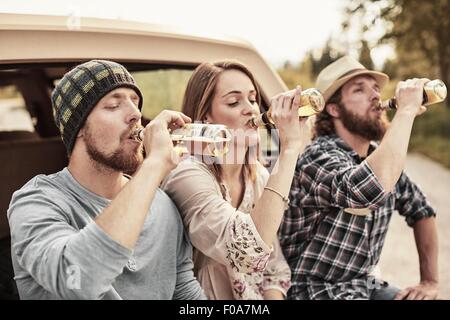 Three people drinking bottled beer in unison Stock Photo