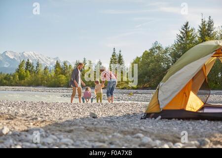Rear view of family playing in river by tent, Wallgau, Bavaria, Germany Stock Photo