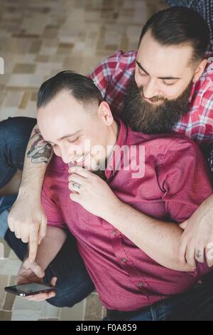 Gay couple using smartphone in bedroom Stock Photo