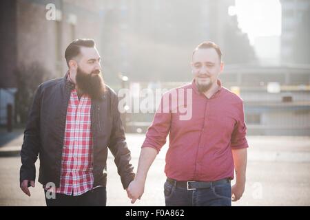 Gay couple walking hand in hand on street Stock Photo