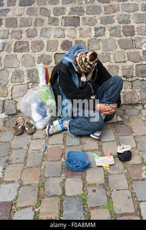 PARIS, FRANCE - JULY 27, 2015: A homeless man is sitting and begging for money on a street in Paris in France Stock Photo