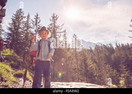 Portrait of young boy standing on rock, in forest