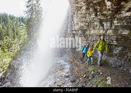 Young family, walking underneath waterfall Stock Photo