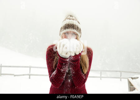 Young woman blowing handful of powder snow Stock Photo