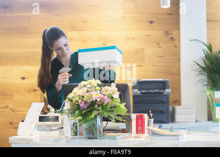 Female sales assistant using barcode reader on shoe box in shoe shop Stock Photo