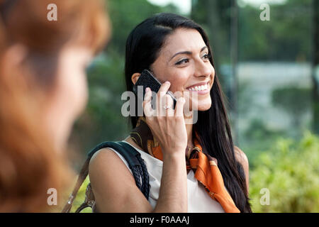 Mid adult woman using smartphone, smiling Stock Photo