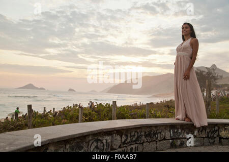 Mid adult woman standing on wall by ocean Stock Photo