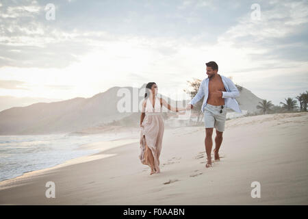 Mid adult couple walking along beach, hand in hand Stock Photo