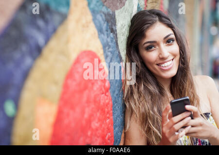 Portrait of young woman using smartphone, smiling