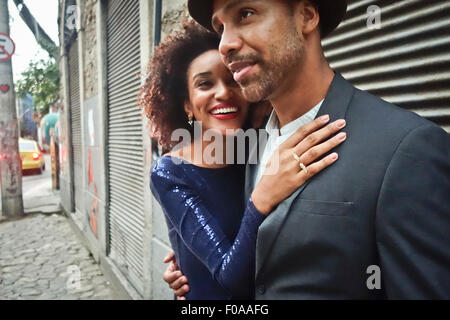 Couple standing together in urban environment, hugging, smiling Stock Photo