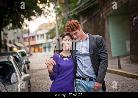 Couple walking along street, arms around each other, smiling