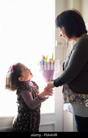 Young girl giving mother flowers Stock Photo