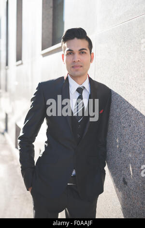 Young businessman leaning against wall Stock Photo