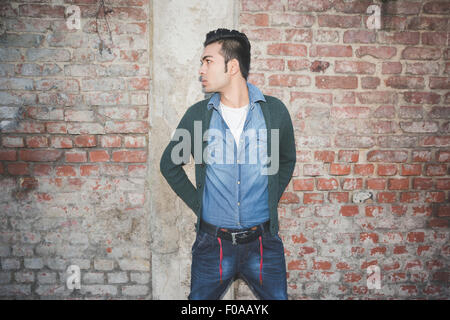 Young man standing against brick wall Stock Photo