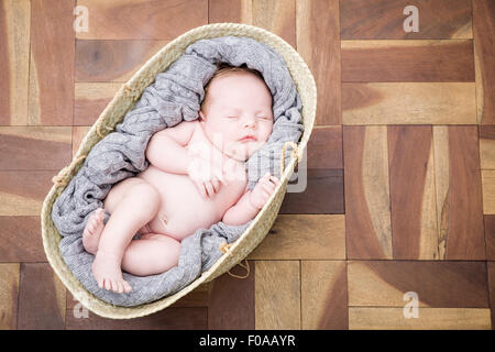 Baby sleeping snugly in moses basket Stock Photo