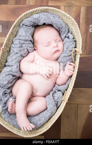 Baby sleeping snugly in moses basket Stock Photo