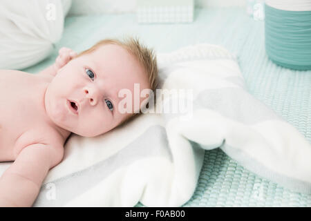 Baby lying down on bed Stock Photo