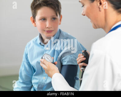 Doctor reading blood pressure of young boy in clinic Stock Photo