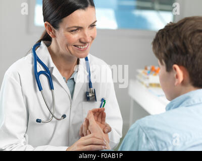 Doctor checking pulse of young boy in clinic Stock Photo