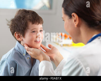 Doctor checking glands of young boy in clinic Stock Photo