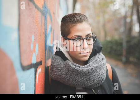 Teenager leaning against graffiti wall Stock Photo