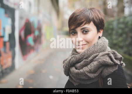 Young woman on street, graffiti wall in background Stock Photo