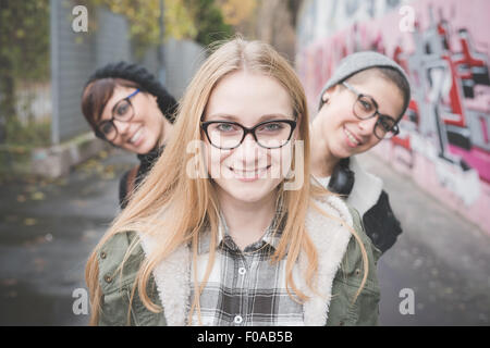 Three sisters on street, graffiti wall in background Stock Photo