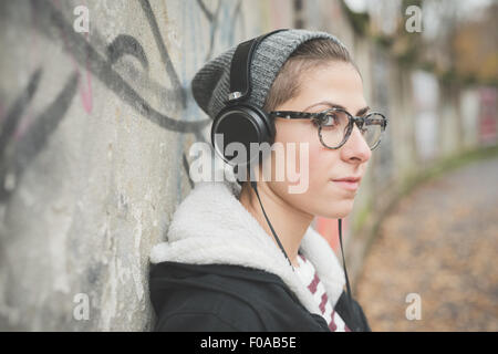 Teenager with headphones by graffiti wall Stock Photo