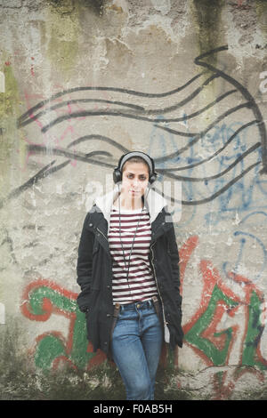 Teenager with headphones by graffiti wall Stock Photo