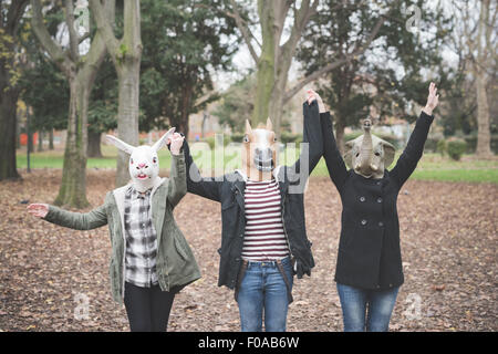 Three sisters wearing animal masks dancing in park Stock Photo