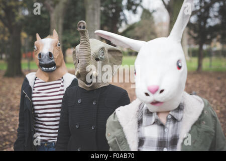 Three sisters wearing animal masks posing in park Stock Photo