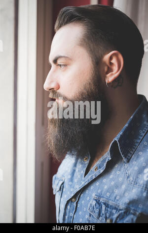 Young bearded man looking out of window Stock Photo
