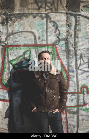 Young bearded man by graffiti wall Stock Photo