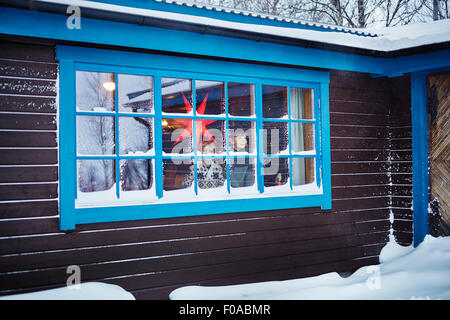 Two brothers looking out of snow covered cabin window at Christmas Stock Photo