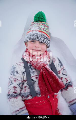 Portrait of cute boy lying in deep snow Stock Photo
