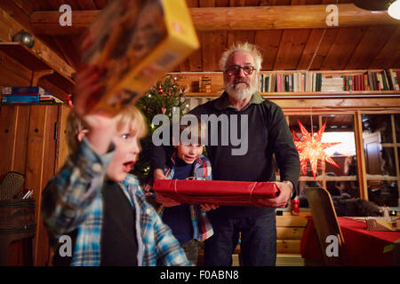 Joyful boy holding up Christmas present Stock Photo