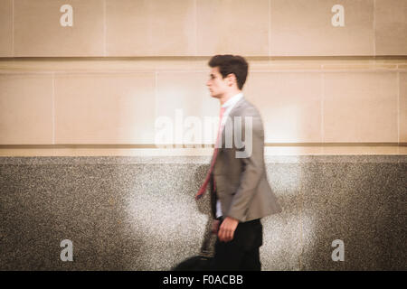 Young city businessman walking on sidewalk Stock Photo