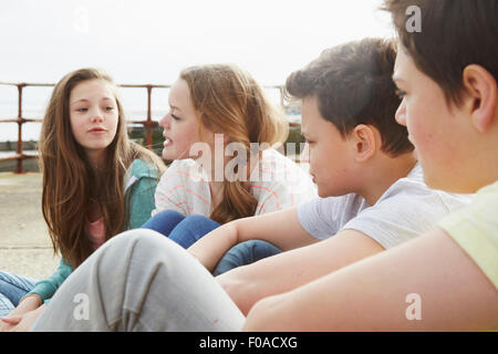 Two boys and two girls sitting outside chatting Stock Photo