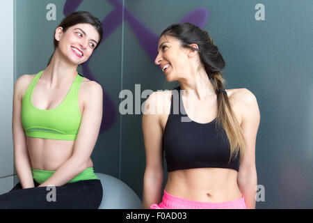 Two young women looking at each other and smiling in gym Stock Photo