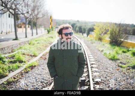 Mid adult man standing on railway track Stock Photo