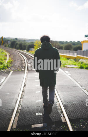 Rear view of mid adult man standing on railway crossing Stock Photo
