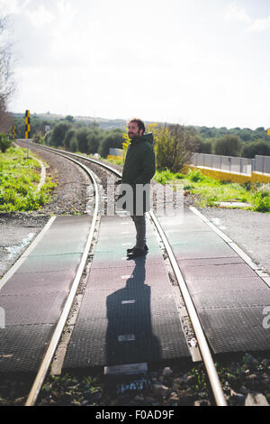 Mid adult man standing on railway crossing Stock Photo