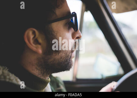 Close up of mid adult man driving and  wearing sunglasses