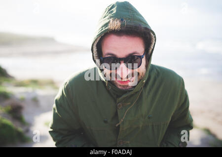 Portrait of mid adult man in hooded jacket at coast Stock Photo