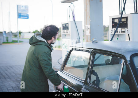 Man using fuel pump for vintage car in gas filling station Stock Photo