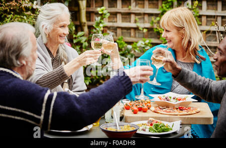 Senior friends making a toast during meal in garden Stock Photo