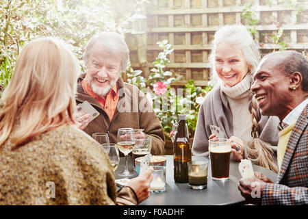 Senior friends drinking and playing cards in garden Stock Photo